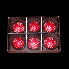 Load image into Gallery viewer, Box of red chocolates with heart designs on a black background